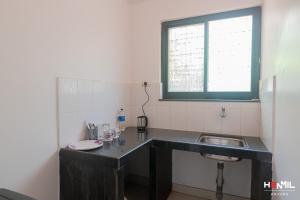 Elle comprend une petite cuisine avec un évier et une fenêtre. dans l'établissement Henmil Anjuna, à Anjuna