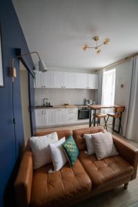 un salon avec un canapé brun dans une cuisine dans l'établissement STERENN Joli T2 - 900m de la gare - Centre Dinan, à Dinan