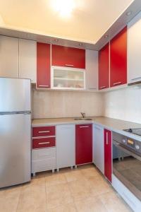 een keuken met rode en witte kasten en een koelkast bij Sofy Center Apartment (Free Parking) in Novi Sad