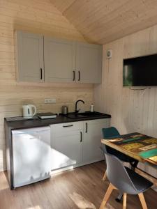 a kitchen with white cabinets and a table with chairs at Przystań Narie in Kretowiny