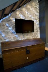 een houten kist met een televisie aan een stenen muur bij Il Piccolo Loft Holiday Home in Palazzolo Acreide