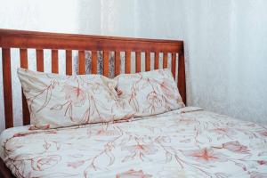 a bed with a wooden headboard and two pillows at Sakura 2BR1B in Kampala