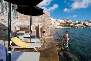 two men are jumping into the water from a building at Hotel Ploes in Ermoupoli