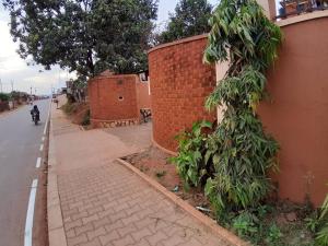 a man riding a motorcycle down a sidewalk next to a brick wall at Umusaale 2BR1B in Kampala