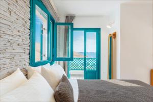 1 dormitorio con ventanas azules y 1 cama con almohadas blancas en Kallidora Home en Astipalea