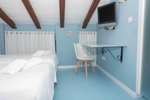 a blue room with two beds and a desk and a tv at Hotel Almunia in Caravaca de la Cruz