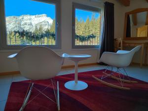 twee stoelen en een tafel in een kamer met twee ramen bij Hotel Elbele Garnì in Folgaria