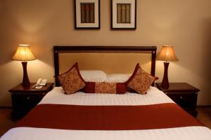 a bedroom with a bed with two lamps and a phone at Crossroads Hotel in Lilongwe +69 photos