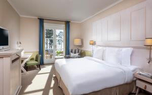 Habitación de hotel con cama blanca grande y escritorio. en Precise Resort Bad Saarow - Golf & Spa en Bad Saarow-Pieskow