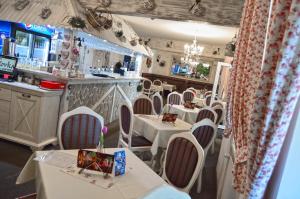 a restaurant with white tables and chairs and a bar at Penzion Batovka u Hoffera in Partizánske