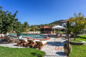 ein Schwimmbecken mit Stühlen, einem Tisch und einem Sonnenschirm in der Unterkunft Ageri Studios in Stafylos