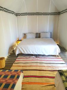 een slaapkamer met een groot wit bed en een tapijt bij Bivouac Erg Chegaga Nomademoi in El Gouera