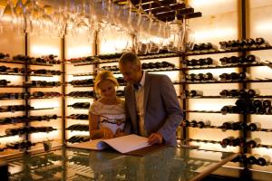 un homme et une femme cherchant un document dans une cave à vin dans l'établissement Hotel Casa da Calçada Relais & Chateaux, à Amarante