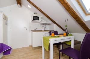 una pequeña cocina con mesa blanca y sillas moradas en Lavender Garden Apartments, en Dubrovnik