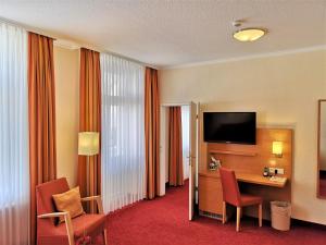 a hotel room with a desk with a television and chairs at Hotel Villa Meeresgruss in Binz