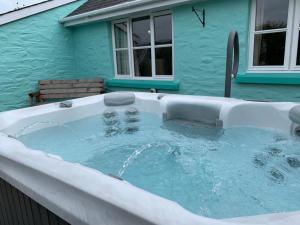 a hot tub in front of a blue house at Canllefaes Cottages in Cardigan