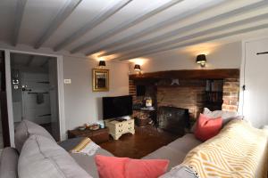 ein Wohnzimmer mit einem Sofa und einem Kamin in der Unterkunft Rose Mullion Cottage in Pett