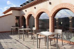 un patio avec des tables et des chaises en face d'un bâtiment dans l'établissement Hotel Palacio Conde del Álamo, à Aroche