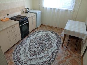 a kitchen with a stove and a rug on the floor at Апартаменты на Первомайская 37 "А" in Semey