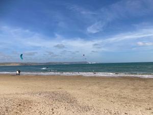 Zwei Leute fliegen Drachen am Strand in der Unterkunft Relax by the Sea in Weymouth