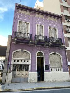 ein violettes Gebäude mit Balkonen in einer Stadtstraße in der Unterkunft Sevilla Home Hotel in Buenos Aires
