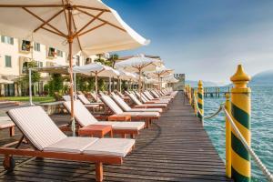 a row of beach chairs and umbrellas on a dock at Grand Hotel Terme Sirmione in Sirmione