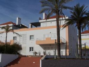 a large white building with palm trees in front of it at Casa da Ria in Cabanas de Tavira