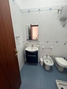 een badkamer met een wastafel, een toilet en een spiegel bij Perla in Cefalù
