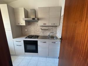 een keuken met witte kasten, een wastafel en een fornuis bij Perla in Cefalù
