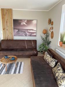 a living room with a brown leather couch and a table at Apartament Jasna in Jastrzębia Góra