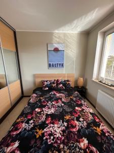 a bedroom with a bed with a floral bedspread at Apartament Jasna in Jastrzębia Góra