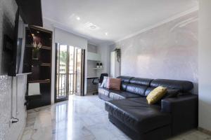 sala de estar con sofá de cuero negro y TV en Renewed and Central Apartment, en Puerto de la Cruz