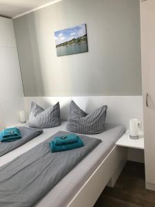 Duas camas num quarto branco com almofadas azuis em Hafen 15 - Ihre Ferienwohnung am Hainer See bei Leipzig em Neukieritzsch
