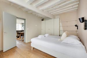 biała sypialnia z łóżkiem i jadalnią w obiekcie Apt archetype parisien dans une rue emblématique ! w Paryżu