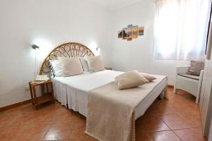 a bedroom with a large white bed and a chair at Casa Basilia in San Teodoro