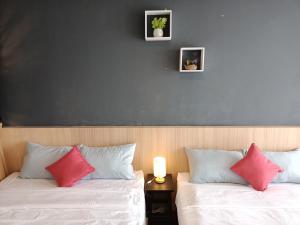 2 łóżka z biało-różowymi poduszkami w pokoju w obiekcie cozy seaview 5 studio apartment w mieście Tanjong Tokong