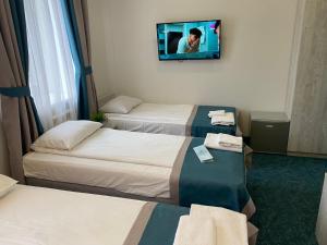 モスクワにあるKirin Hotelのベッド3台、薄型テレビが備わるホテルルームです。