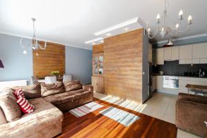 a living room with a brown couch and a kitchen at Apartament Karmelowy z tarasem - Dream Apart in Wisła