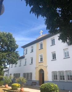 um grande edifício branco com uma cruz em cima em Hostal San Cristobal - Pontedeume em Puentedeume