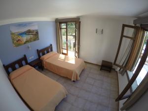 a room with two beds and a window at Hostal Playa in Cala Santanyi