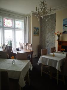 a dining room with two tables and chairs and windows at Durham House in Beer
