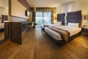 a hotel room with two beds and a desk at Rome Airport Hotel Fiumicino in Fiumicino