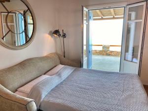 a bedroom with a bed with a mirror and a window at Blue Calm Luxury Villa in Sifnos in Artemonas