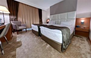 a hotel room with a large bed and a desk at Riva Reşatbey Luxury Hotel in Adana