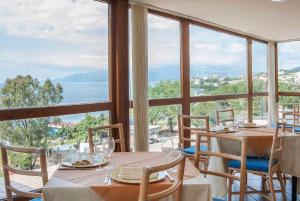 comedor con mesa y sillas y ventana grande en Hotel Orion, en Villammare