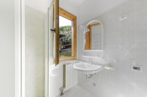ein weißes Badezimmer mit Waschbecken und Fenster in der Unterkunft Villaggio Colombo V6 in Marina dʼAndora