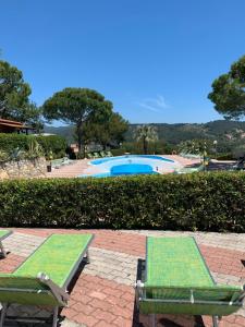 two green chairs sitting next to a swimming pool at Villaggio Colombo V5 in Marina dʼAndora +12 photos