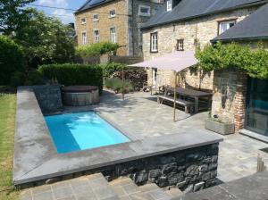 a backyard with a swimming pool and an umbrella at Maison de charme à Crupet et le gîte la suite in Crupet