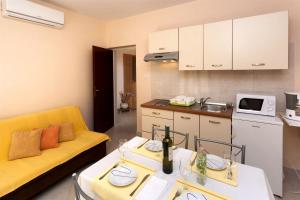 a living room with a yellow couch and a kitchen at Apartment Vlado in Poreč