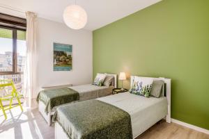 two beds in a room with green walls at Family & Friends Rooms with shared bathroom in Padova